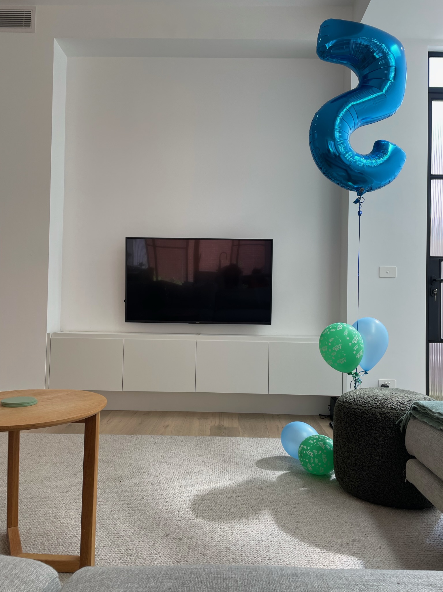 Bright minimalist living room featuring custom built-in TV cabinet, white feature wall and light timber flooring — BQ HOMES Melbourne renovation